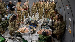 Airmen gather around medical simulation mannequins on a KC-46 Pegasus aircraft 