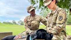 Spc. Dejzanna Smith, left, a mental health specialist assigned to Bayne-Jones Army Community Hospital, and Master Sgt. Sunny, the hospital’s facility dog, comfort Spc. Mariya Yevdokimova