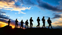 A silhouette of service members conducting a patrol at sunset. 