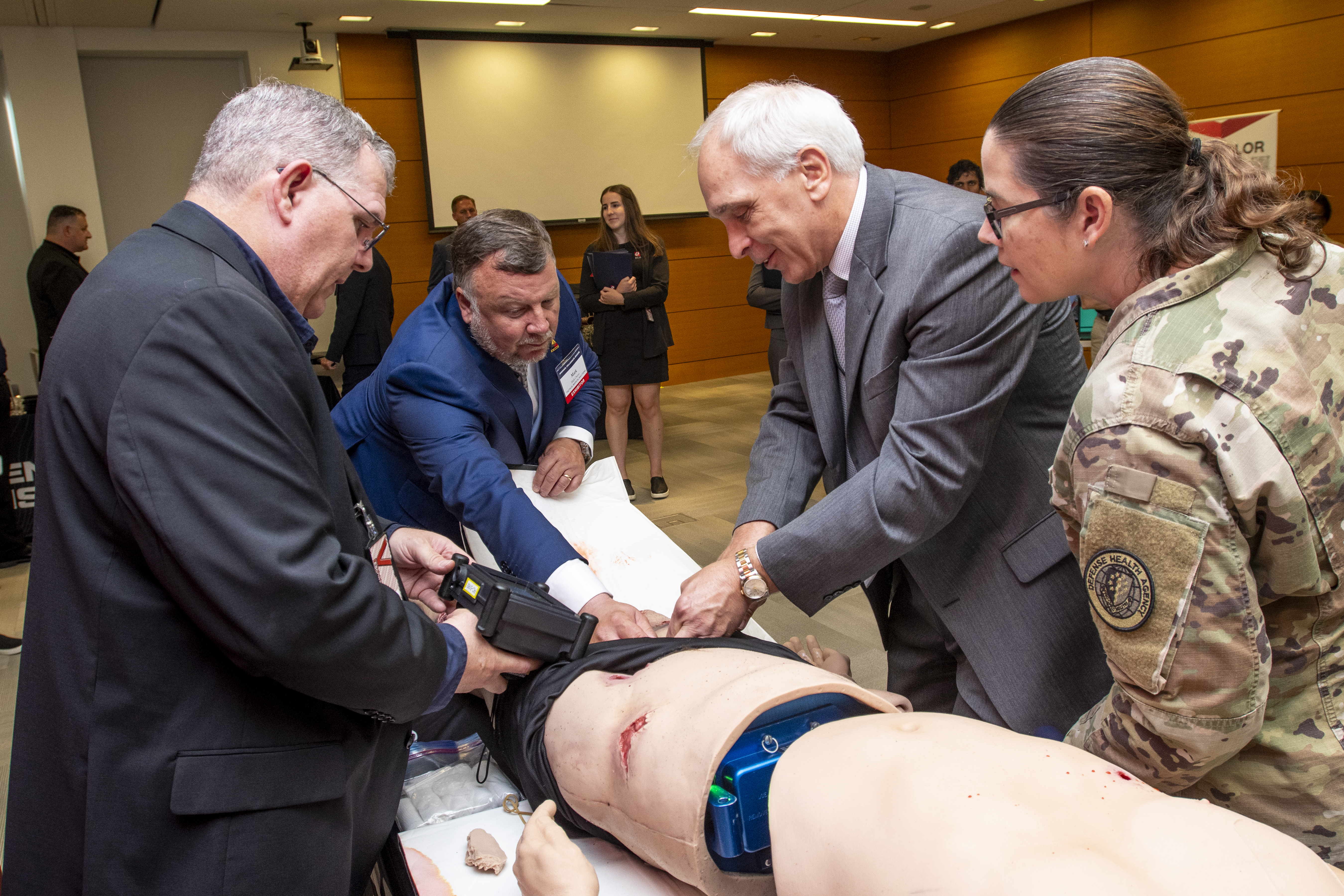 Donald Johnson, assistant director of support for the Defense Health Agency, applies a tourniquet on a simulation mannequin during a tour for DHA senior leaders at the Medical Simulation Expo at headquarters on Aug. 3, 2023. U.S. Army Col. Maria Molina, director of education and training, DHA, looks on as representatives of TACMED Simulation provide instruction. (Photo: Robert Hammer)