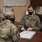 Two military women sitting at a desk and discussing documents
