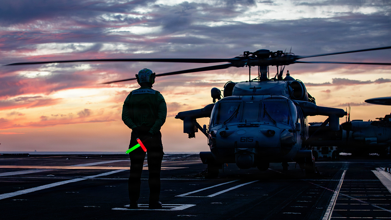 A U.S. Sailor stands by to signal to an MH-60S Sea Hawk helicopter, attached to Helicopter Sea Combat Squadron 9, on the flight deck of the world’s largest aircraft carrier, USS Gerald R. Ford (CVN 78), during Operation Epic Fury, March 15, 2026. (U.S. Navy photo)