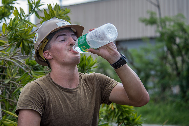 Builder 3rd Class, assigned to Mobile Construction Battalion (NMCB) 1, detachment Guam, drinks water while reconstructing a roof for a home that was damaged during Typhoon Mangkhut. U.S. Navy photo by Mass Communication Specialist 2nd Class Kelsey J. Hockenberger)  
