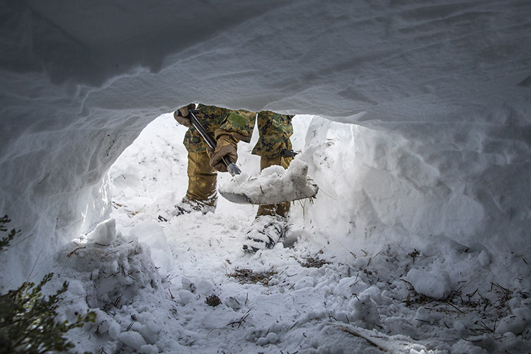 A U.S. Marine with the Winter Mountain Leaders Course digs out a snow cave shelter during a 24-hour survival training event at Marine Corps Mountain Warfare Training Center, Bridgeport, California, Jan. 15, 2022. The purpose of the Winter Mountain Leaders Course is to train ground combat arms military occupational specialties in mountain warfare tactics, techniques and procedures to serve effectively as force multipliers to their units during combat operations in complex, compartmentalized, mountainous terrain. (U.S. Marine Corps photo by Lance Cpl. Joshua Sechser)