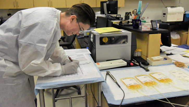 Technician takes notes next to convalescent plasma samples.