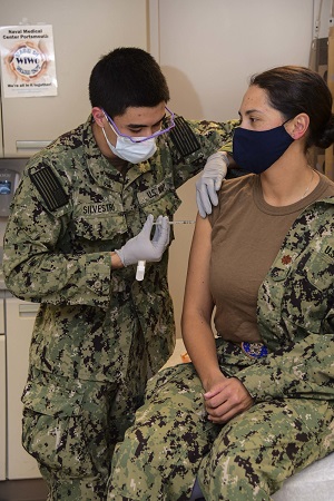Navy Hospitalman gives vaccine to soldier in her right arm