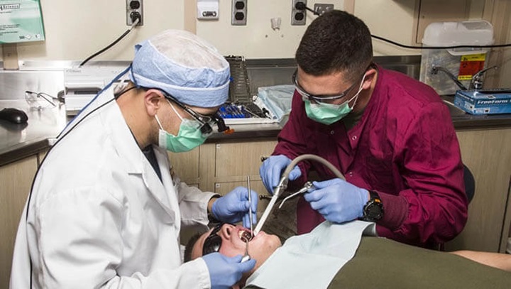 Image of U.S. Navy Hospitalman Justin Sobleskie (right), and U.S. Navy Lt. Matthew Roberts, USS Carter Hall dental department head, do dental work on aboard the USS Carter Hall (LSD 50) while at sea.