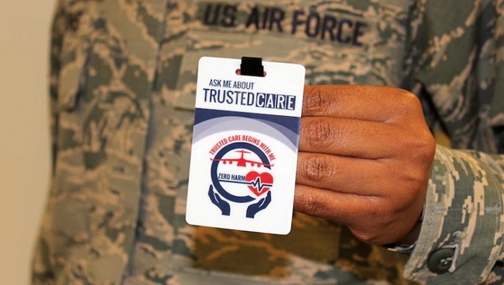 Image of soldier holding up a badge that says "Trusted Care.".
