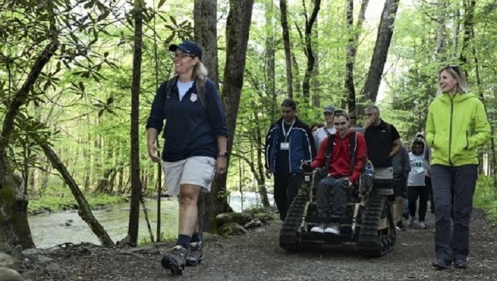 Image of Group of people walking and on wheelchairs through the forest.