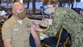 Military health personnel wearing a face mask and a face shield giving the COVID-19 vaccine