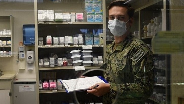 Image of Soldier wearing mask, marking items off in supply room. Click to open a larger version of the image.