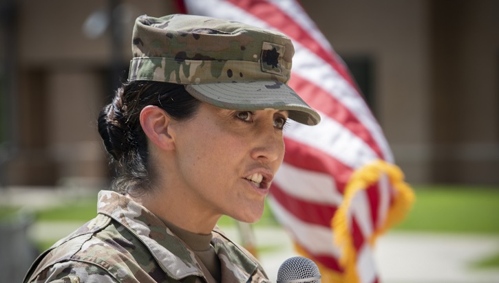 Soldier in front of flag speaking into microphone