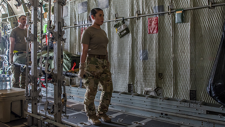 Image of Two military personnel loading equipment onto an aircraft. Click to open a larger version of the image.