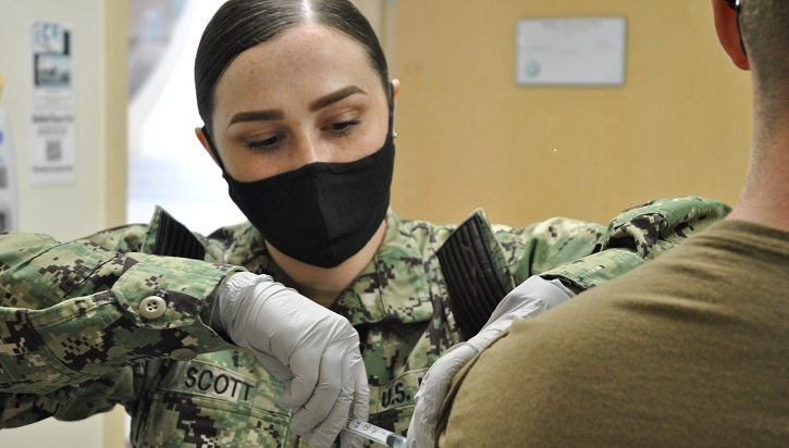 Image of Technician wearing a mask, giving a shot to a soldier. Click to open a larger version of the image.