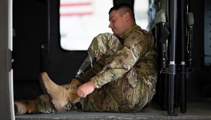 Image of Soldier with leg prosthesis putting on his shoe. .