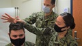 Three soldiers, wearing masks, demonstrating a hearing test