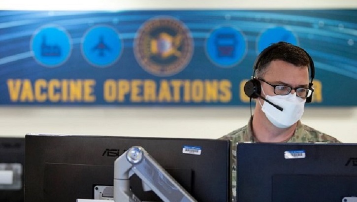 Image of Soldier wearing mask, sitting in front of computer monitors. Click to open a larger version of the image.