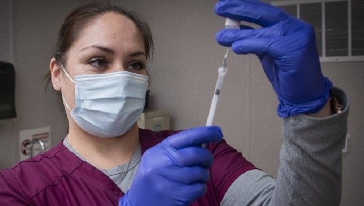 Image of Medical technician getting a syringe ready to give a vaccine. Click to open a larger version of the image.