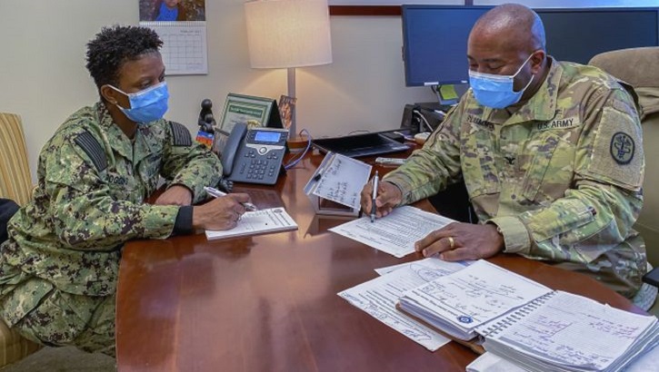 Image of Two military personnel, wearing masks, in a meeting. Click to open a larger version of the image.