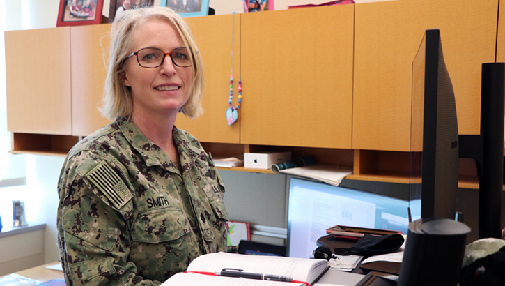 Image of Military officer sitting at her desk and smiling. Click to open a larger version of the image.