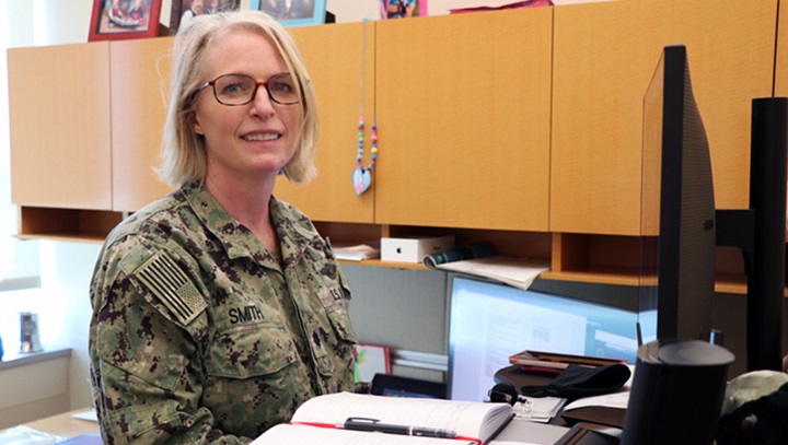 Image of Military officer sitting at her desk and smiling.