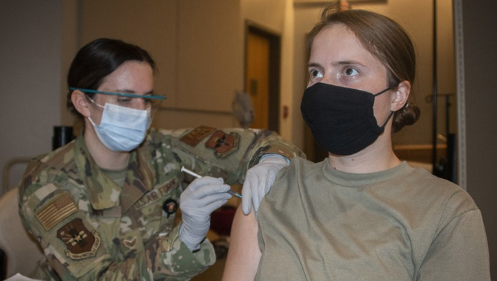 Image of Medical personnel giving a vaccine to a soldier in her right arm. Click to open a larger version of the image.
