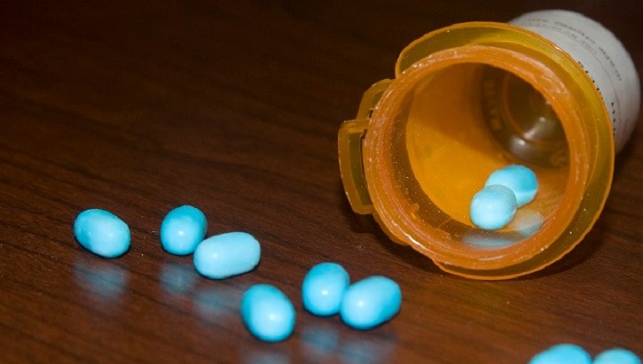 Image of An open bottle of pills, with some spilling out on the table.
