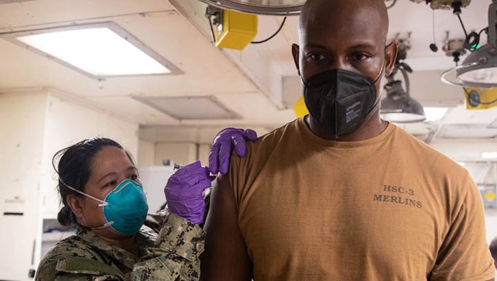 Image of Hospital Corpsman 1st Class Mary Ashcraft, assigned to the combat ship USS Tulsa, administers a COVID-19 vaccine booster to Aviation Machinist Mate 1st Class Anthony Johnson Jan. 10, 2022, at Apra Harbor, Guam. (Photo: Mass Communication Specialist Petty Officer 1st Class Devin M. Langer, Command Destroyer Squadron 7). Click to open a larger version of the image.