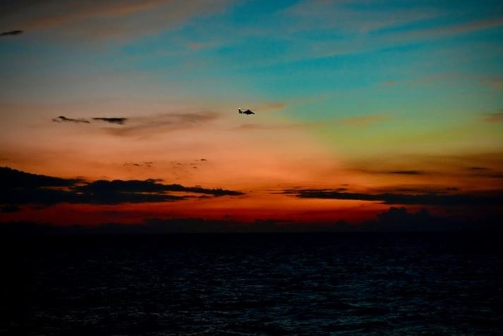 A U.S. Coast Guard MH-65 Dolphin helicopter flies over the sunset off the northern coast of Haiti in Nov. 2021