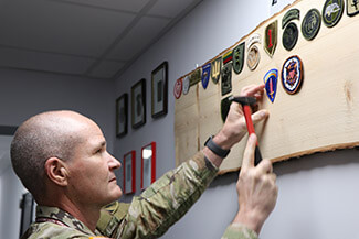 Military personnel nailing crest on patch board