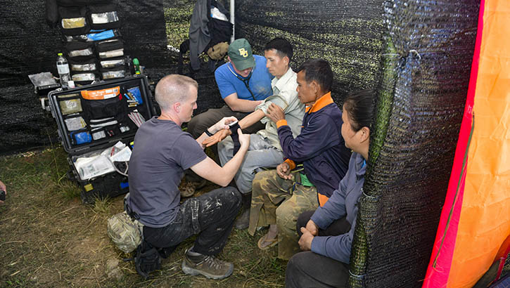 U.S. Army Sgt. 1st Class Mathew Maxwell (Left) and U.S. Capt. Brian Ahern, medical personnel assigned to a Defense POW/MIA Accounting Agency (DPAA) recovery team, check the pulse of a local villager during excavation operations in the Houaphan province, Laos, Feb. 5, 2019.