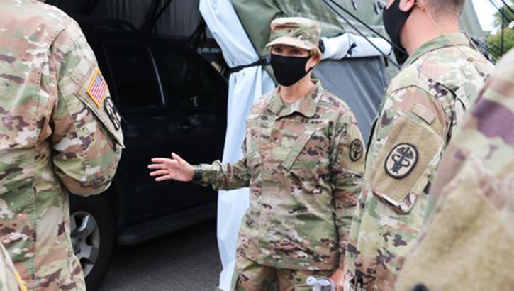 Image of Soldier in mask speaking to other soldiers. Click to open a larger version of the image.