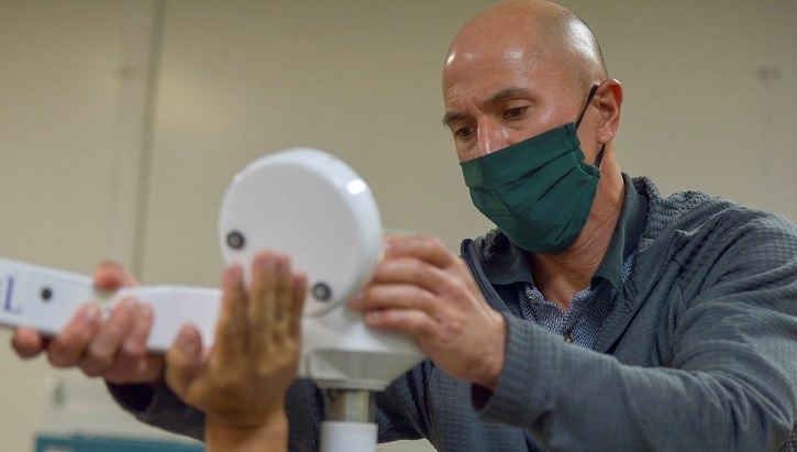 Technician wearing mask, adjusting medical equipment