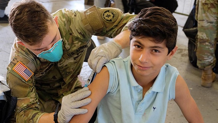 An Army medic administers an MMR vaccine to an Afghan evacuee.