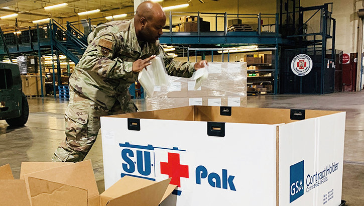 Image of Military member in warehouse, packing a large box.