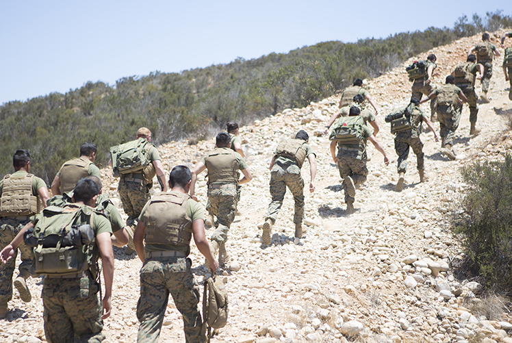 Image of U.S. Marines sprint uphill during a field training exercise at Marine Corps Air Station Miramar, California. to maintain contact with an aviation combat element, teaching and sustaining their proficiency in setting up and maintaining communication equipment.  (Photo Courtesy: U.S. Marine Corps).