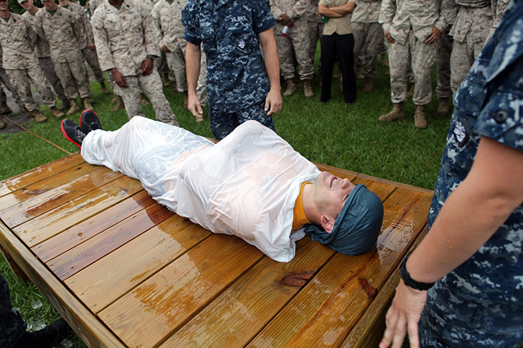 Image of Navy Petty Officer 3rd Class Ryan Adams is being used as an example victim for cooling a heat casualty at the bi-annual hot weather standard operating procedure training aboard Marine Corps Base Camp Lejeune, N.C., Aug. 24. Adams is demonstrating the "burrito" method used to cool a heat related injury victim. Photo by Pfc. Joshua Grant.