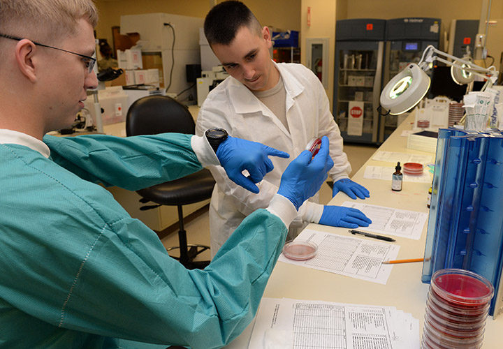 Image of The (left to right) Senior Airman Austin Shrewsbury, 88th Diagnostics and Therapeutic Squadron medical laboratory technician, works with student, Airman 1st Class Taylor Altman, 88th Diagnostics and Therapeutic Squadron medical laboratory technician, to identify bacteria of patient’s cultures inside the microbiology laboratory at Wright-Patterson Air Force Base medical center June 30, 2017. .