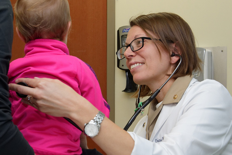 Image of A Navy doctor examines a young patient. Click to open a larger version of the image.