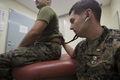 A U.S. naval officer listens through his stethoscope to hear his patient’s lungs