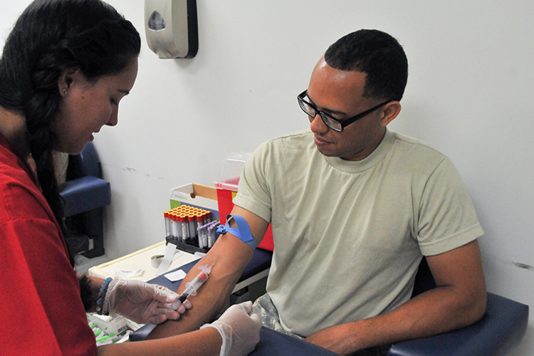 Image of Spc. Jayson Sanchez of the Army Reserve’s 77th Sustainment Brigade receives a blood draw from phlebotomist Nikole Horrell.
