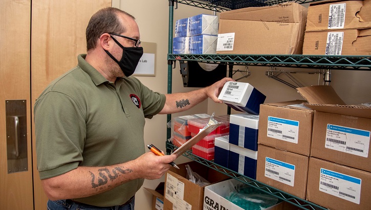 Image of Man wearing mask checking inventory on shelves. Click to open a larger version of the image.
