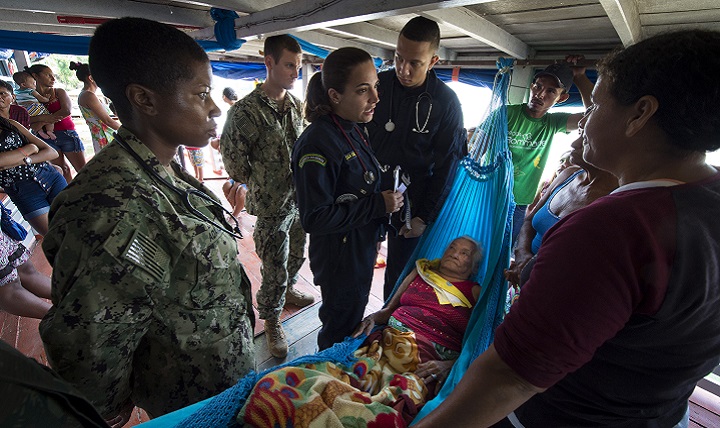 U.S. Navy Lt. Cmdr. Nehkonti Adams, an infectious diseases specialist, left, and U.S. Navy Lt. Gregory Condos, an internal medicine specialist, middle, work with 2nd Lt. Raissa Vieira Sanchez, a Brazilian medical officer, right, to diagnose an elderly woman on her houseboat near a remote village along the Amazon River in Brazil. (U.S. Navy photo by Mass Communication Specialist 2nd Class Andrew Brame)
