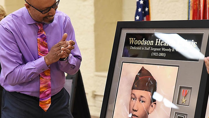 Image of Stephen Woodson looks at the plaque painting of his father, Staff Sgt. Waverly Woodson Jr., a World War II First U.S. Army combat medic hero, following the unveiling of it during a renaming dedication ceremony at Rock Island Arsenal, Illinois, April 14. The health clinic was renamed Woodson Health Clinic. (Photo: Jon Micheal Connor, ASC Public Affairs) .
