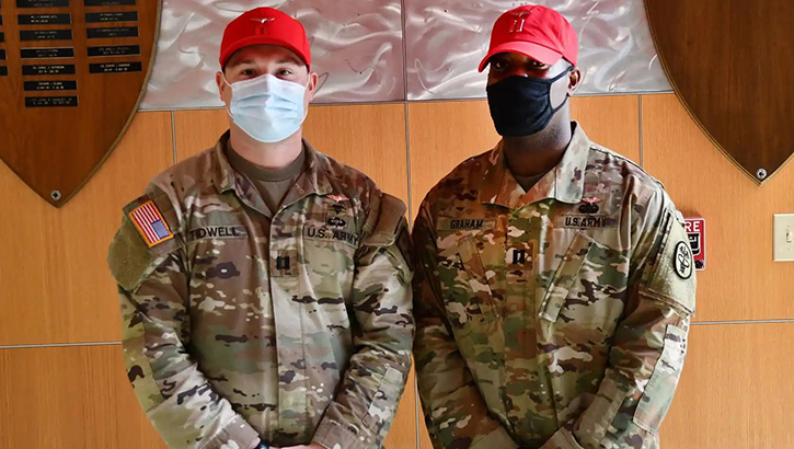 Image of Two military personnel in masks pose for picture.