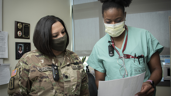 Military health personnel wearing face mask reviewing a patient's record