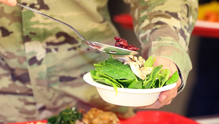 Image of Soldier holding a bowl of lettuce and vegetables.