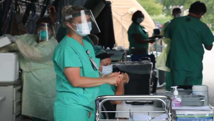 Image of Medical personnel set up in an outside military tent. Click to open a larger version of the image.