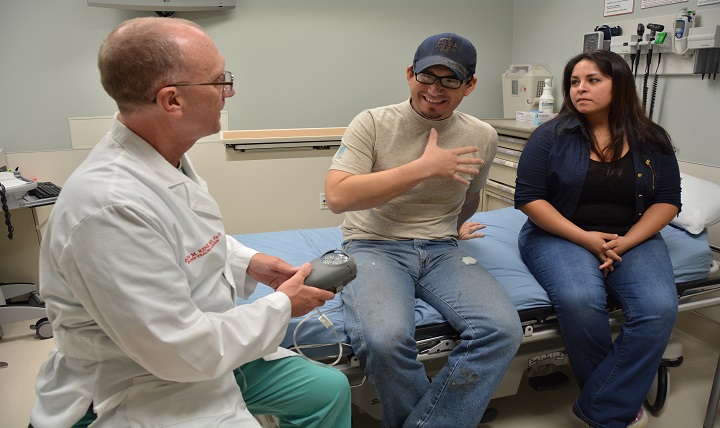 Army Col. Evan Renz explains the function of a vacuum-assisted closure device to Indalecio Morales while Morales' wife, Maribel, looks on in the U.S. Army Institute of Surgical Research Burn Center at San Antonio Military Medical Center.