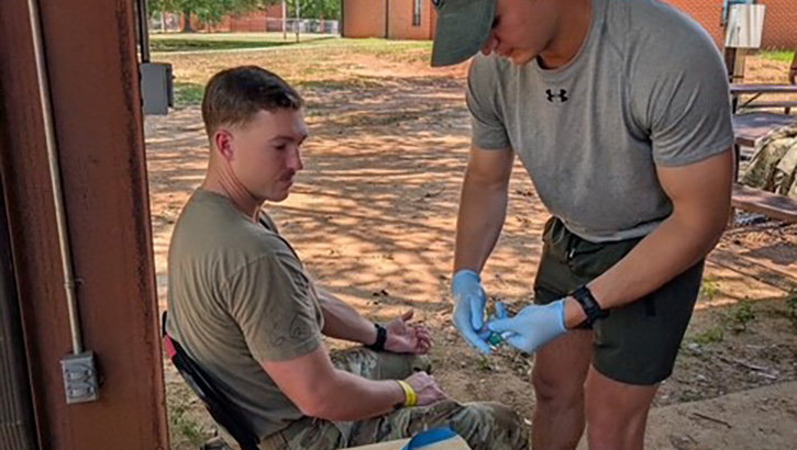 A phlebotomist with the U.S. Army Research Institute of Environmental Medicine prepares to draw blood from a volunteer Soldier prior to physical training
